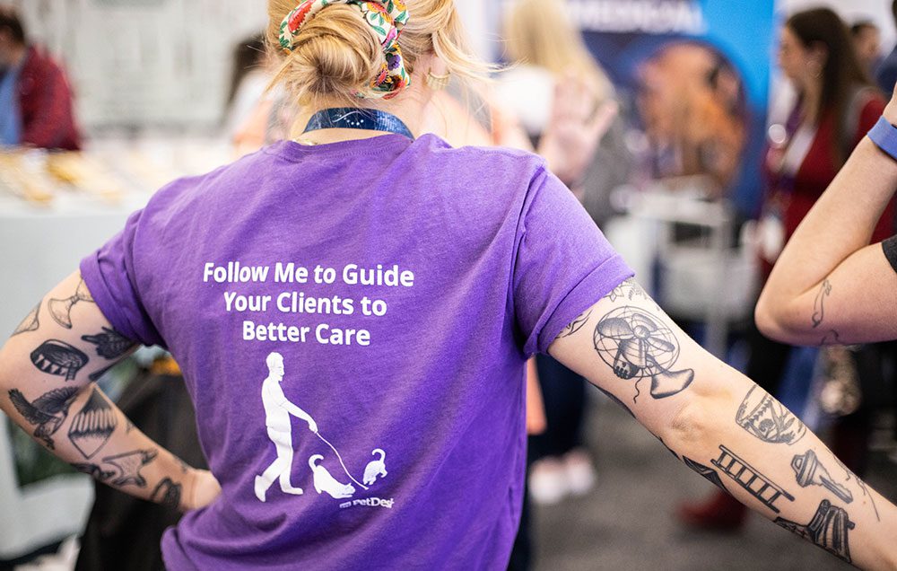 0223_WVC-2023_Exhibit-2857-cr-sm closeup of back of PetDesk t-shirt that reads Follow me to guide your clients to better care