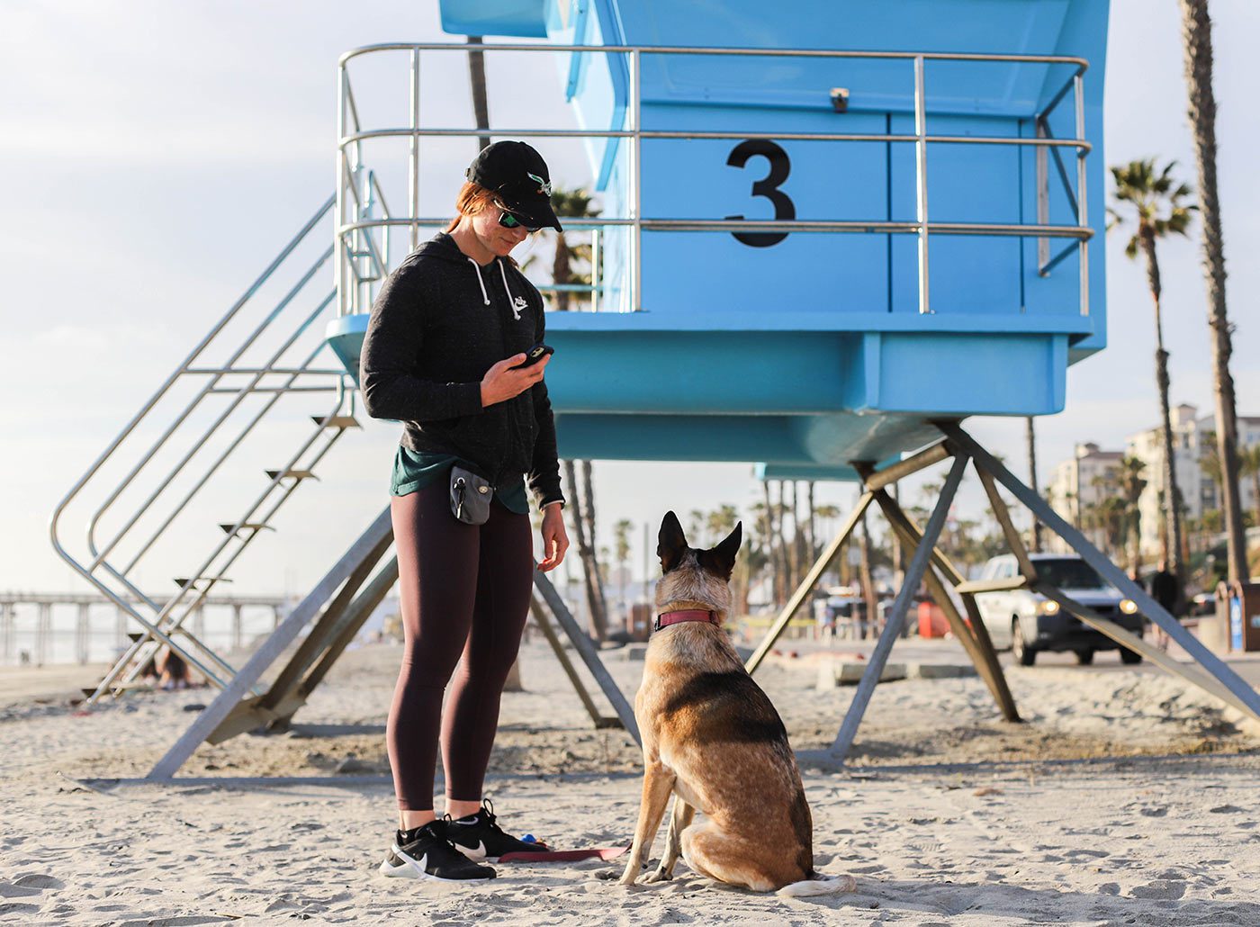 person-with-dog-next-to-lifeguard-tower-at-beach-13 pet parent with dog standing next to lifeguard tower