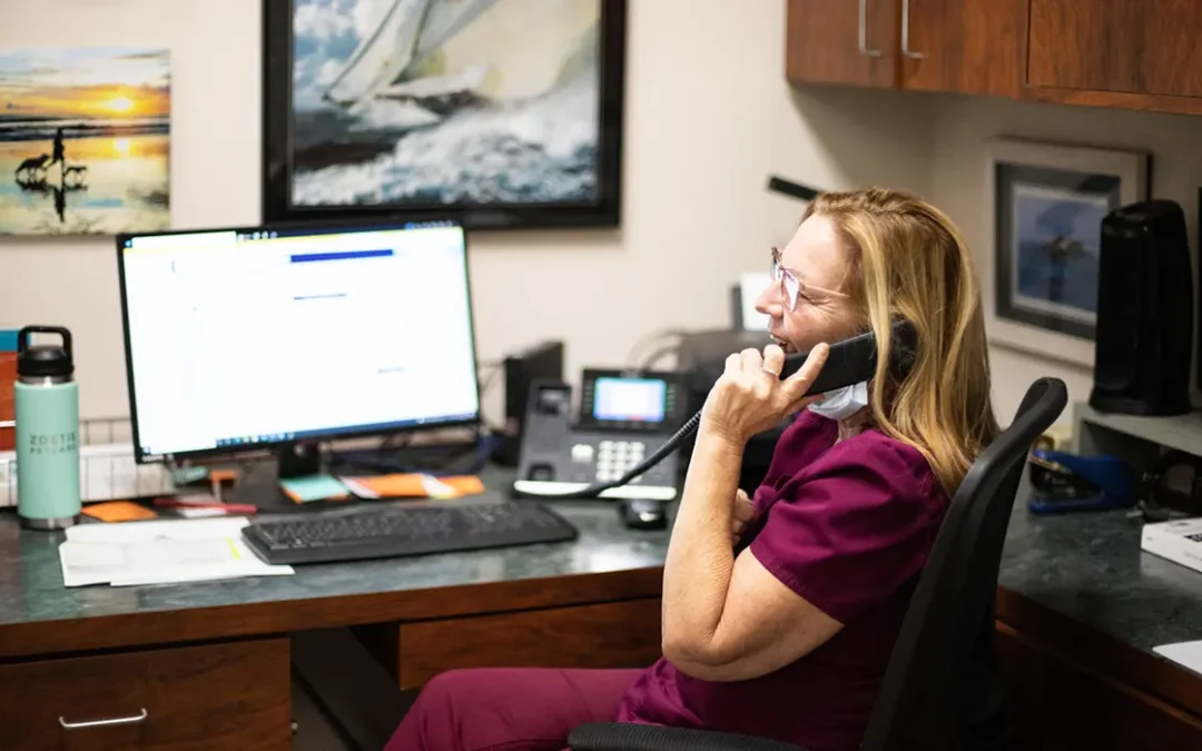 Happy Veterinary CSR chatting on the phone at their desk