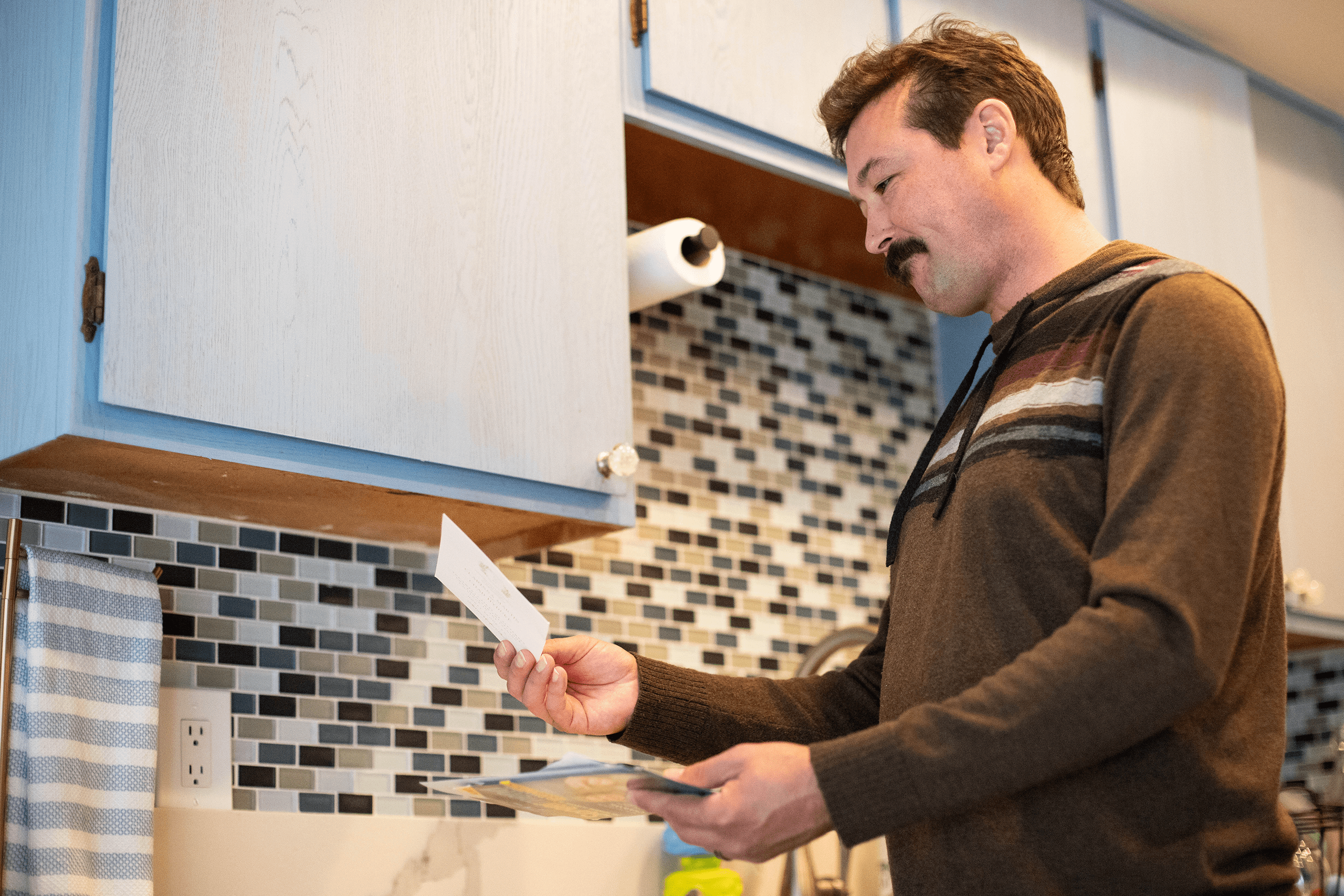 Pet parent looking at a postcard reminder they received in the mail Pet parent looking at a postcard reminder they received in the mail