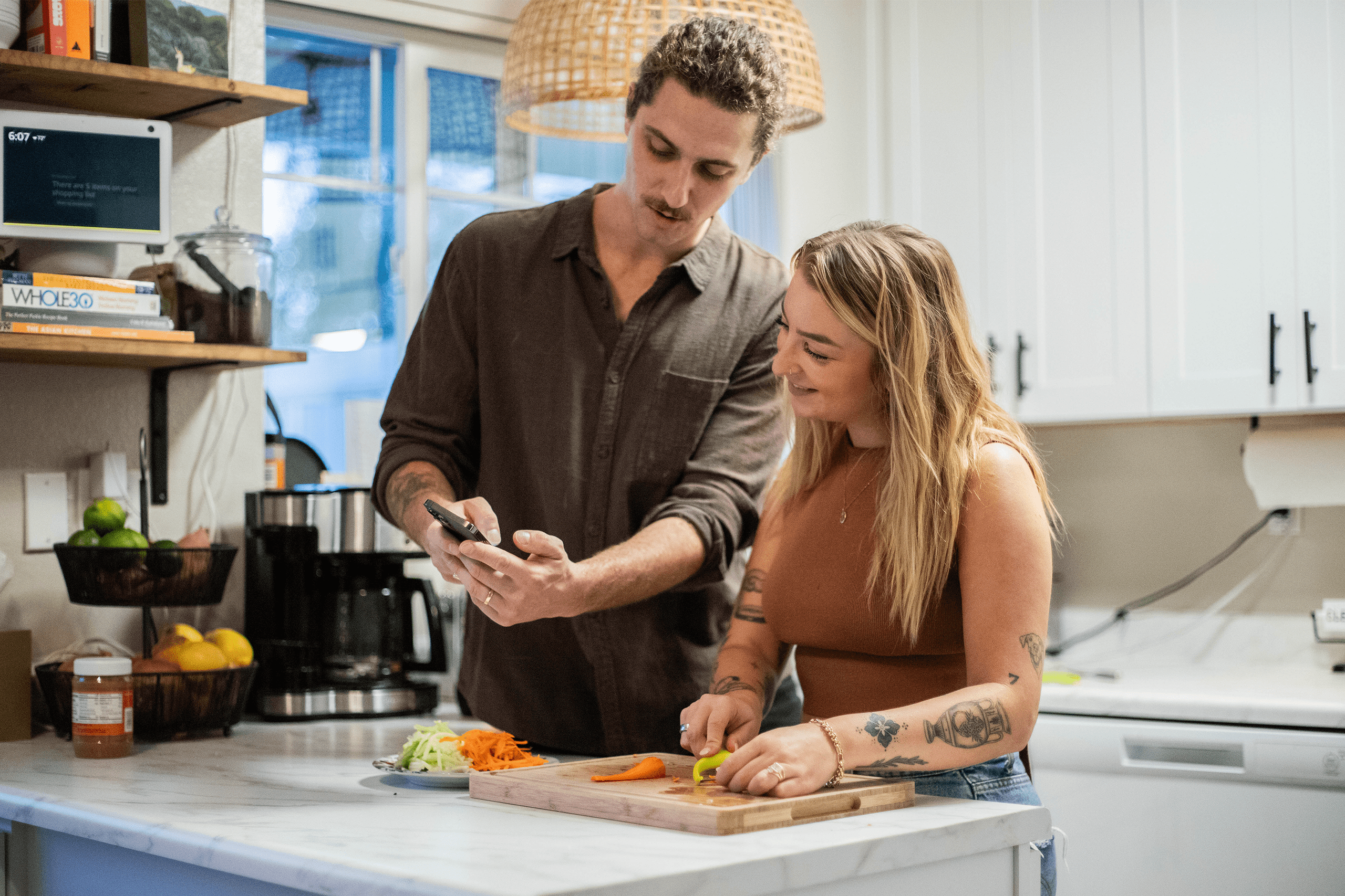 Pet parents chatting while looking at phone and cooking dinner Pet parents chatting while looking at phone and cooking dinner